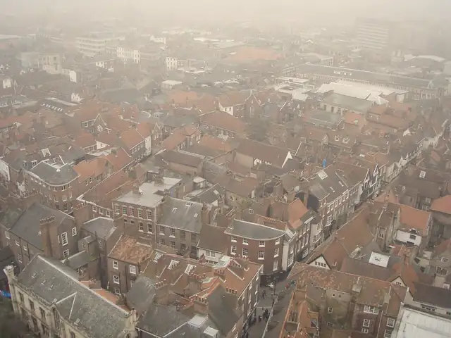 Misty view over York city-centre streets and roofs of red pantiles and grey slate, seen from York Minster